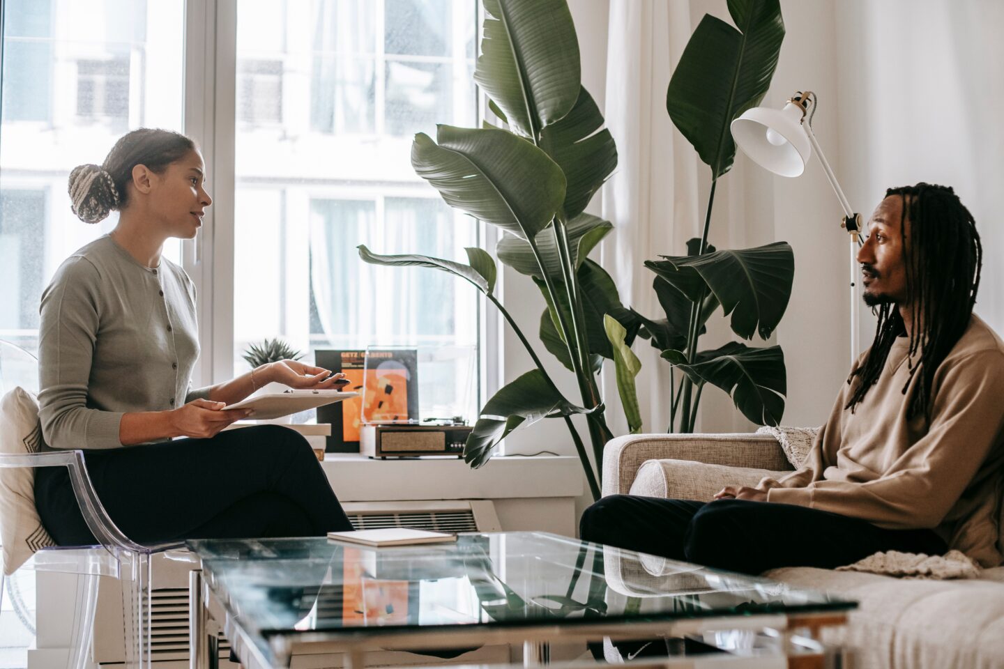 A therapist and client in conversation in a calm, plant-filled office